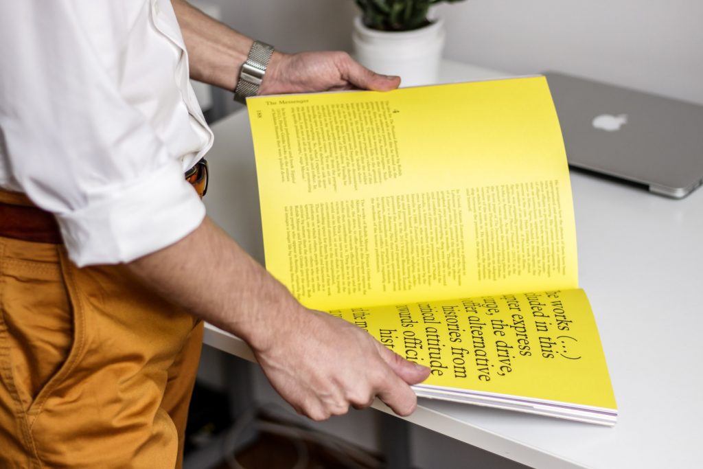Homem segurando livro de design amarelo.